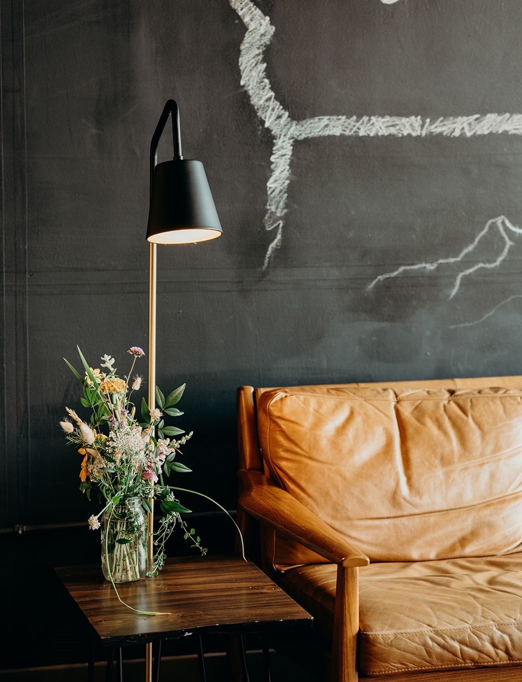 ENSO lounge with a leather sofa, brass lamp and wildflowers